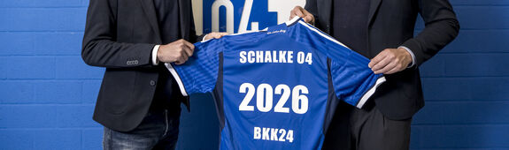 Vertreter von BKK24 und schalke 04 halten Trikot mit der Nummer 2026 in die Höhe